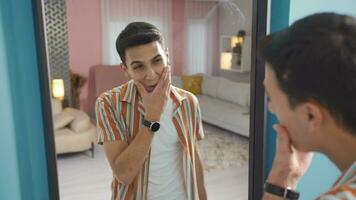 Handsome man looks at himself in the mirror and admires it. video