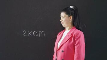 Woman writing interview on blackboard looks sad at camera. video