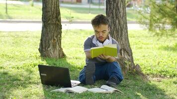 frustrado e nervoso Faculdade anão aluna estudando ao ar livre dentro a parque. video
