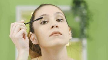 Jeune femme appliquant mascara à sa cils. video