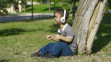 enano joven hombre sentado en el piso con alegría escucha a música. video