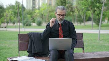 aburrido de trabajo empresario sentado al aire libre en el parque. video