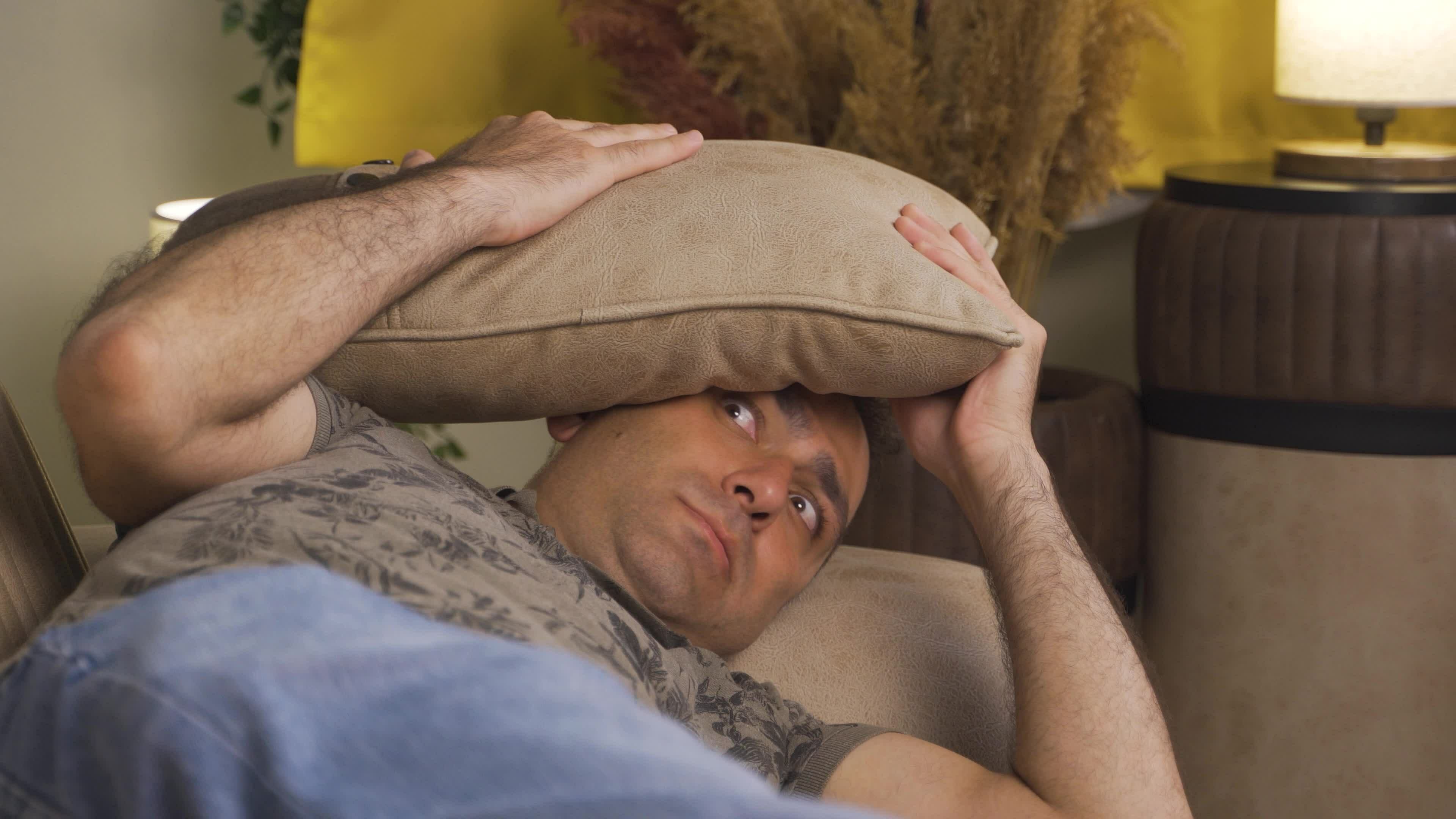 The man who presses the pillows on his head with fear. 32966458 Stock