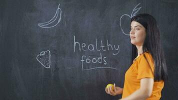 mulher escrevendo saudável alimentos em quadro-negro parece às Câmera feliz e cheio do vida. video