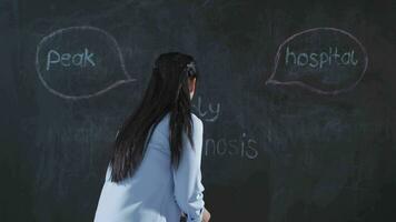 Woman writing Early diagnosis on blackboard makes positive gesture. video