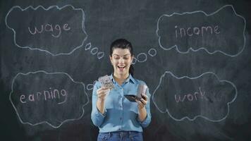 Woman writing Salary on blackboard looks with happy and profitable expression. video