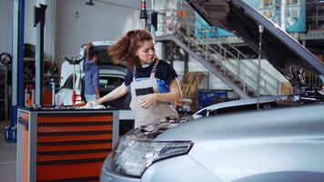 gekwalificeerd ingenieur in reparatie winkel gebruik makend van koppel moersleutel naar vastdraaien schroeven na opening auto naar controleren haar parameters gedurende onderhoud. deskundige gebruik makend van professioneel gereedschap in garage naar herstellen opgepakt voertuig video