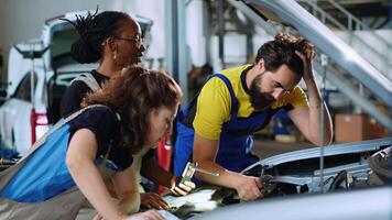 squadra di tecnici nel auto servizio utilizzando ispezione lampada per fix danneggiato automobile. colleghi servizio rotto veicolo, controllo per malfunzionamento trasmissione utilizzando professionale utensili video