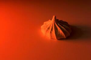 One meringue cookie in red light on a light background. photo