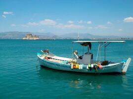 un pequeño pescar barco en un cuerpo de agua. veneciano castillo de bourtzi en el fondo, Nauplia ciudad, argólida, peloponeso, Grecia. foto