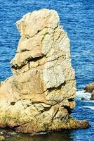 a rock formation in the ocean near the shore photo