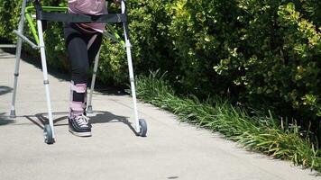 child with walking frame and knee orthosis outdoor video