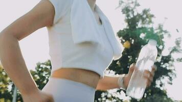 Young woman athlete takes a break, drinking water, out on a run on a hot day. video