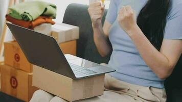 mujer joven dueña de una pequeña empresa comprando en línea en casa. tomando nota de los pedidos de los clientes con teléfonos móviles. pyme emprendedor o concepto de estilo de vida independiente. video