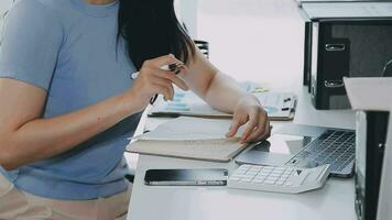 Charming Young asian businesswoman sitting on laptop computer in the office, making report calculating balance Internal Revenue Service checking document. video