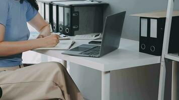 Charming Young asian businesswoman sitting on laptop computer in the office, making report calculating balance Internal Revenue Service checking document. video