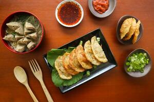 fried wonton. wonton on plate with chili oil. Shrimp or meat dumpling soup with mustard , green onions, on table photo