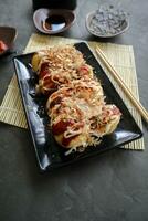 takoyaki es un japonés alimento, hecho desde trigo harina masa, pulpo carne, o otro rellenos, servido con salsa, mayonesa y Adición en el formar de katsuobushi o madera pescado virutas. foto