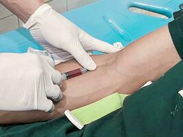 un masculino enfermero es inyectando un dolor relevista anestésico dentro un del paciente mano foto