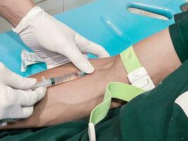 A male nurse is injecting a pain reliever anesthetic into a patient's hand photo