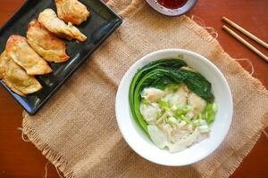 wonton soup. Bowl of wonton soup with chili oil. Shrimp or meat dumpling soup with mustard , green onions, photo