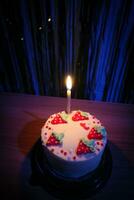 cumpleaños pastel con asperja fresa y uno velas en un azul antecedentes foto