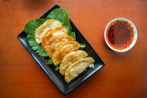 fried wonton. wonton on plate with chili oil. Shrimp or meat dumpling soup with mustard , green onions, on table photo