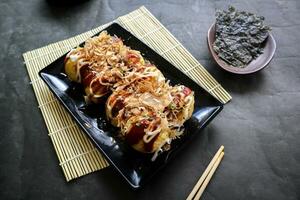 takoyaki es un japonés alimento, hecho desde trigo harina masa, pulpo carne, o otro rellenos, servido con salsa, mayonesa y Adición en el formar de katsuobushi o madera pescado virutas. foto