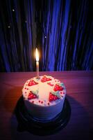 birthday cake with sprinkles strawberry and one candles on a blue background photo