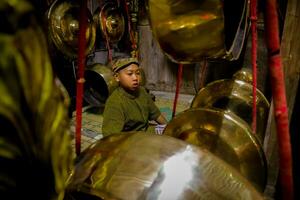 javanés Niños realizar javanés gamelan música en klaten, Indonesia. javanés chico jugando gamelan gong foto