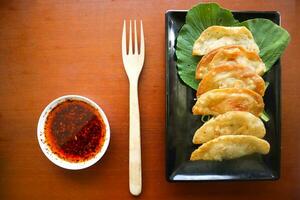 fried wonton. wonton on plate with chili oil. Shrimp or meat dumpling soup with mustard , green onions, on table photo