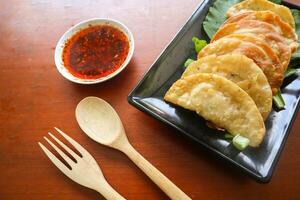 fried wonton. wonton on plate with chili oil. Shrimp or meat dumpling soup with mustard , green onions, on table photo