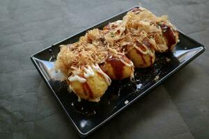 takoyaki es un japonés alimento, hecho desde trigo harina masa, pulpo carne, o otro rellenos, servido con salsa, mayonesa y Adición en el formar de katsuobushi o madera pescado virutas. foto