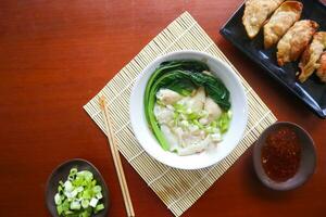 wonton soup. Bowl of wonton soup with chili oil. Shrimp or meat dumpling soup with mustard , green onions, photo