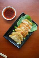 fried wonton. wonton on plate with chili oil. Shrimp or meat dumpling soup with mustard , green onions, on table photo