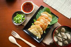 fried wonton. wonton on plate with chili oil. Shrimp or meat dumpling soup with mustard , green onions, on table photo