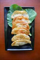 fried wonton. wonton on plate with chili oil. Shrimp or meat dumpling soup with mustard , green onions, on table photo