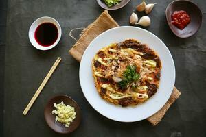 okonomiyaki, Traditional Japanese Pizza, Japanese hot plate pizza from Okonomiyaki. made of flour which is diluted with water or dashi, plus cabbage, chicken eggs, seafood and fried in a teppan photo