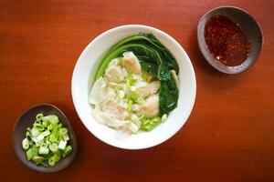 wonton soup. Bowl of wonton soup with chili oil. Shrimp or meat dumpling soup with mustard , green onions, photo