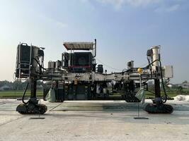 Slipform paver machine on road work at construction site. Highway concrete paving in the new quarter. Repairing concrete roads using new technology. machine photo