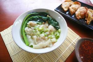 wonton soup. Bowl of wonton soup with chili oil. Shrimp or meat dumpling soup with mustard , green onions, photo
