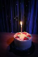 cumpleaños pastel con asperja fresa y uno velas en un azul antecedentes foto