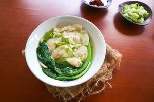 wonton soup. Bowl of wonton soup with chili oil. Shrimp or meat dumpling soup with mustard , green onions, photo