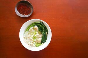 wonton soup. Bowl of wonton soup with chili oil. Shrimp or meat dumpling soup with mustard , green onions, photo