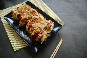 takoyaki es un japonés alimento, hecho desde trigo harina masa, pulpo carne, o otro rellenos, servido con salsa, mayonesa y Adición en el formar de katsuobushi o madera pescado virutas. foto