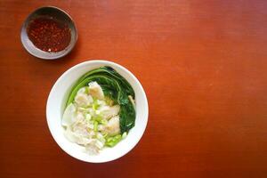 wonton soup. Bowl of wonton soup with chili oil. Shrimp or meat dumpling soup with mustard , green onions, photo