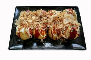 Takoyaki is a Japanese food, made from wheat flour dough, octopus meat, or other fillings, served with sauce, mayonnaise and topping in the form of katsuobushi or wood fish shavings. photo