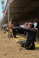 Klaten, Indonesia, august 15, 2023. male and female participants, dressed in Javanese custom pulled his bow by squinting to achieve concentration of target accuracy in traditional Javanese arrow trad. photo