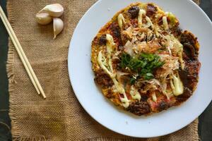 okonomiyaki, Traditional Japanese Pizza, Japanese hot plate pizza from Okonomiyaki. made of flour which is diluted with water or dashi, plus cabbage, chicken eggs, seafood and fried in a teppan photo