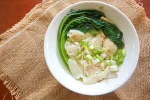 wonton soup. Bowl of wonton soup with chili oil. Shrimp or meat dumpling soup with mustard , green onions, photo